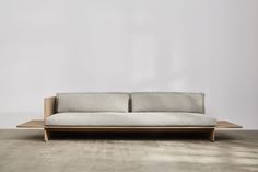 a white couch sitting on top of a wooden floor next to a gray wall in an empty room