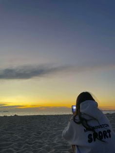 a person on the beach with a cell phone in their hand, taking a photo