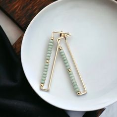 "Elevate your look with our Handmade Rectangle Hoop Gold & Mint earrings. Crafted with a luxurious gold frame and delicate mint green seed beads, these earrings offer understated elegance and sophistication. * 14k Gold Filled Wire * Earrings measure 1.75\" long * Mint Green Seed Beads * Polished to a High Shine * Sent in a Ribboned Gift Box with Polishing Cloth * Handmade in Montana   ----- OUR MATERIALS -----  *STERLING SILVER - Experience the elegance of Sterling Silver, a metal that combines versatility with a sophisticated look. This durable and lightweight alloy is perfect for everyday wear, offering a timeless appeal. Our jewelry is crafted from .925 certified sterling silver, guaranteeing its authenticity and longevity. *14K GOLD FILLED - Gold-filled pieces have the same appearance Mint Earrings, Meditation Accessories, Essential Oil Jewelry, Handmade Jewelry Gift, Understated Elegance, Tea Accessories, Wire Earrings, Jewelry Packaging, Accessories Bracelets