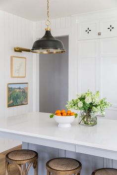 a kitchen island with three stools and a bowl of fruit on the counter top