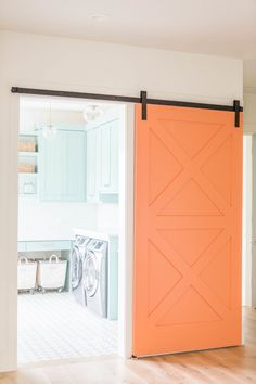 an orange door is opened to reveal a washer and dryer in the laundry room