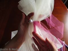 a person is tying a white ribbon on a piece of organe with some scissors