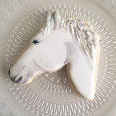 a cookie shaped like a horse on top of a glass plate with white frosting