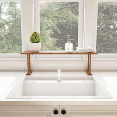 a white sink sitting under a window next to a wooden shelf