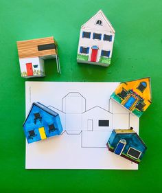 three paper houses sitting on top of a piece of paper