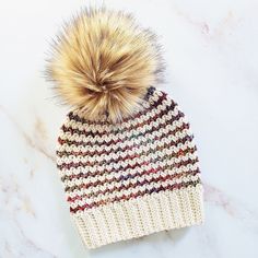 a knitted hat with a pom - pom sitting on top of it