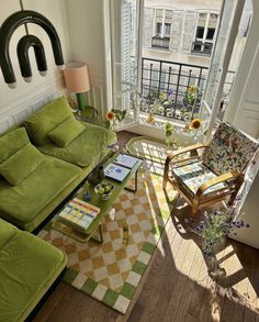 a living room filled with furniture and a green couch next to a large open window