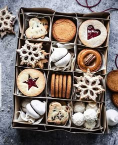 an open box filled with different types of cookies and pastries on top of a table