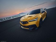 a yellow sports car parked on the side of a race track at sunset or dawn