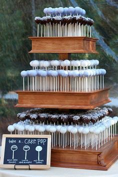 a three tiered cake with icing on it and a sign that says cake pop