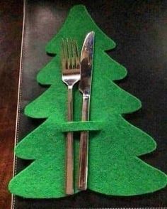 a fork and knife sitting on top of a green place mat next to a christmas tree