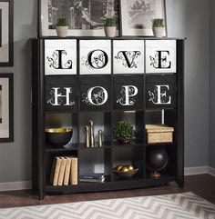 a shelf with pictures and books on it in a room that is decorated with black and white decor