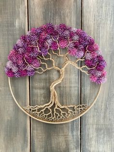 a wire tree with purple flowers in the shape of a moon on a wooden background