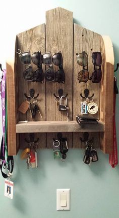 a wooden shelf with sunglasses and other items hanging on the wall next to a light switch