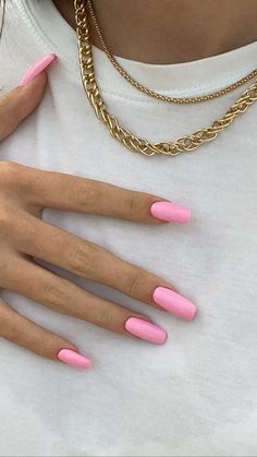 a woman with pink nail polish on her hands and gold chains around her neck, wearing a white t - shirt