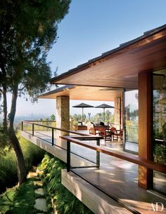 an outdoor patio with tables and umbrellas on the deck overlooking the trees in the distance