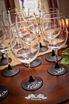 several wine glasses are lined up on a table with place mats for the names and date