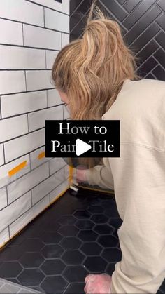 a woman is using a tile grout to install a wall