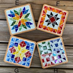 four coasters made out of stained glass on a wooden surface with letters e, f, and f