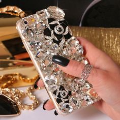 a woman holding up her phone case with jewels on it