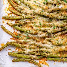 asparagus covered in cheese and parmesan on a sheet of parchment paper