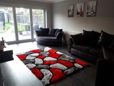 a living room filled with black furniture and red rug