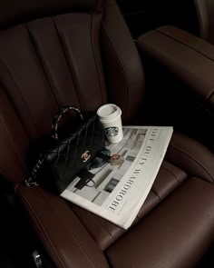 a coffee cup sitting on top of a magazine in the back seat of a car