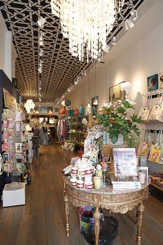 the inside of a store with lots of items on tables and chandeliers hanging from the ceiling