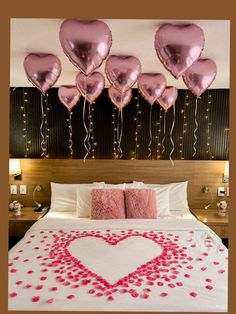 a bed with pink heart shaped balloons hanging from the headboard and pillows on it