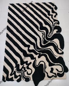 a black and white area rug with wavy lines on the top, in front of a tile floor