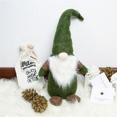 a green and white stuffed gnome next to some pine cones, an ornament and a bag