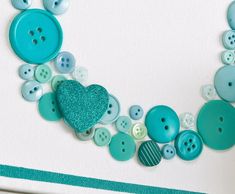 there is a blue heart surrounded by buttons on the white board with green trim around it