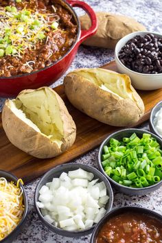 baked potatoes, black beans, shredded cheese and green onions on a cutting board with other ingredients