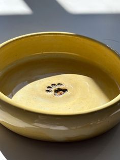 a yellow bowl sitting on top of a table with a paw print in the center