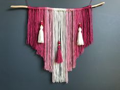 a pink and white wall hanging with tassels