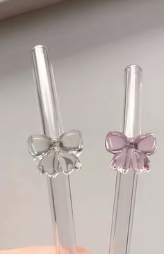 two clear glass vases with bows on the top one is pink and the other is silver