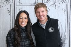 a man and woman standing next to each other in front of a white paneled wall