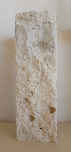 a white rock with holes in it on a table next to a light colored wall