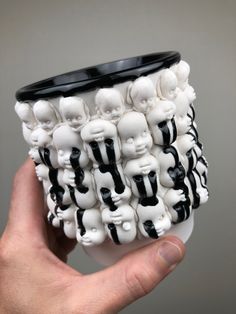 a hand holding a coffee cup with black and white skulls on it's sides