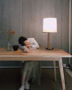 a person sitting at a table with a lamp on it