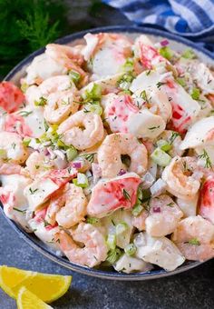 a bowl filled with shrimp salad and garnished with fresh herbs on the side