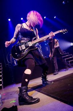 a woman with pink hair playing guitar on stage