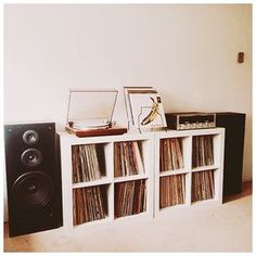 an entertainment center with record players, speakers and bookshelves in front of a white wall