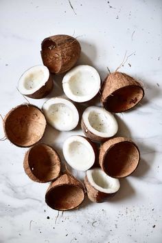 coconuts are cut in half and placed on a white marble counter top, with the tops peeled off