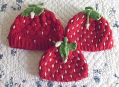 three knitted strawberries sitting on top of a bed