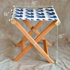 a wooden stool with a blue and white patterned seat cover on it's legs