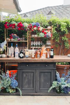 an outdoor bar is decorated with flowers and bottles