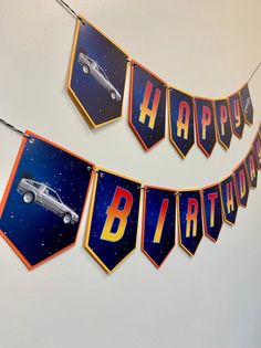 happy birthday banner hanging on the wall with cars and stars in the sky behind it