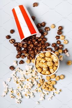 popcorn spilled out of a red and white striped paper bag next to a bowl of popcorn