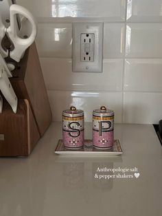 two pink salt and pepper shakers sitting on top of a counter next to an electric outlet